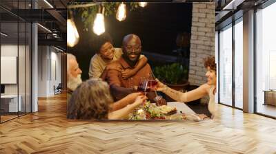 Happy young man with son toasting with his wife over served table during outdoor family dinner while enjoying spending time together Wall mural