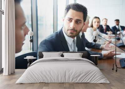 Head and shoulders portrait of handsome businessman looking at colleague while sitting at meeting table in conference room, copy space Wall mural