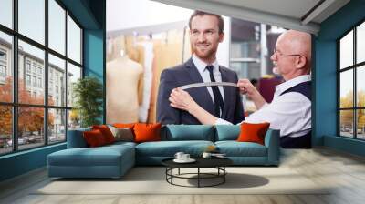 Portrait of handsome man smiling during model fitting of tailored suit in atelier Wall mural