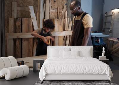 Portrait of little boy building wooden birdhouse while bonding with father in workshop Wall mural