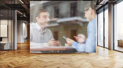 portrait of two excited friends meeting in cafe and chatting cheerfully, shot from behind glass wind Wall mural