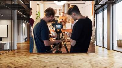 Rear view of videographer and his assistant adjusting video camera for shooting of commercial or cooking masterclass in the kitchen Wall mural