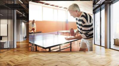 Senior tennis player going to throw and hit ping pong ball while holding it in hand Wall mural