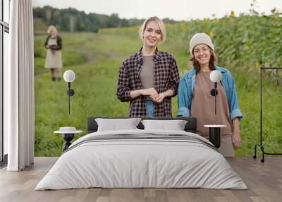 Two cheerful female farmers in workwear looking at you with smiles at farm Wall mural