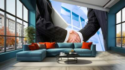 two partners shaking hands at meeting in front of building Wall mural