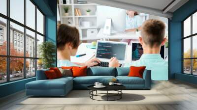 Two schoolboys and schoolgirl sitting by desks in front of computers Wall mural