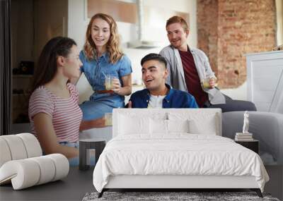 Two young couples with drinks sitting on sofa and having talk at home Wall mural