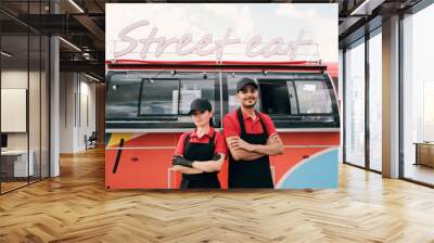 Two young successful colleagues in uniform standing against street food truck Wall mural