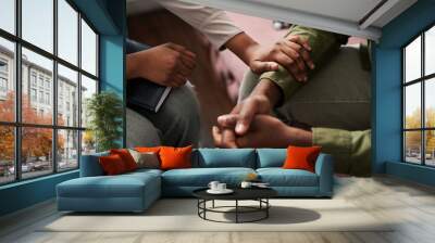 Young African American female psychologist keeping hand of wrist of male patient sitting in front of her and sharing his problems Wall mural