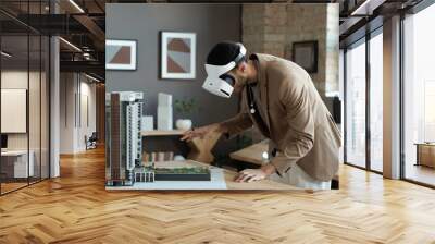 Young architect in vr headset bending over house layout while standing by table and making presentation of new architectural project Wall mural