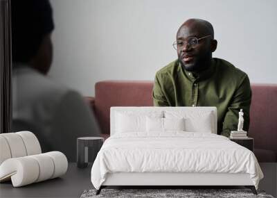 Young black man in casualwear sitting on couch and explaining his emotions and worries during talk with psychoanalyst Wall mural