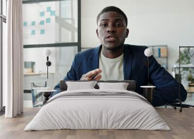 Young confident broker or lawyer explaining something to client during online communication in video chat while sitting in front of laptop Wall mural