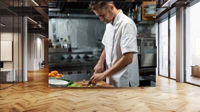 Young professional chef of modern restaurant in uniform cutting vegetables Wall mural