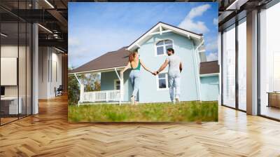 Young romantic lovers holding by hands while moving to their new house Wall mural