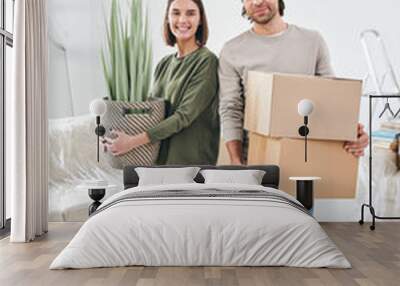 Young smiling woman with domestic plant and her husband with two packed boxes Wall mural