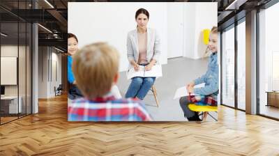 Young teacher and two little schoolgirls listening to classmate during group discussion Wall mural