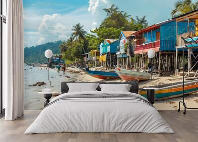 Coastal fishing village with colorful wooden shacks, fishing boats moored along a sandy shore, and children playing in the surf Wall mural