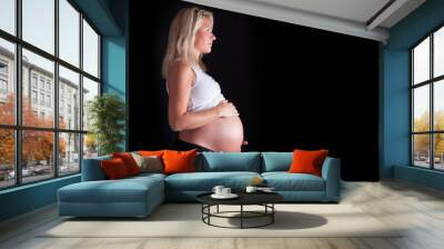 Pregnant woman touching her belly with hands. Isolated over a bl Wall mural