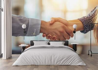 Close-up of a business handshake between a man and a woman, sealing a deal in a bright, professional office. Wall mural