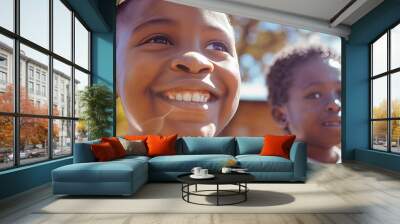 A young Black girl smiles brightly as she looks up at something off-camera. Wall mural