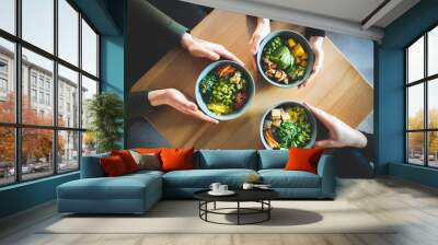 Healthy breakfast. Three friends are holding a bowl. Fresh salad with avocado, grains, beans, vegetables and seafood close-up. Superfood, clean eating, diet food concept Wall mural