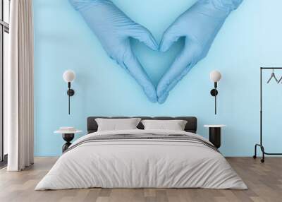 Caring hands of doctor in medical gloves making heart shape on blue background. Minimal medical concept. Flat lay, top view, copy space Wall mural