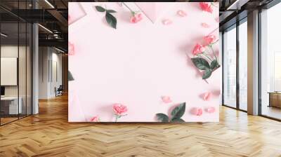 Flowers composition romantic. Pink envelopes and flowers roses, rose petals on pastel pink background. Flat lay, top view, copy space Wall mural