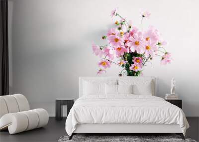 Fresh summer bouquet of pink cosmos flowers in white vase on white wood shelf on white wall background. Floral home decor. Wall mural