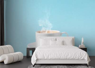 Steaming coffee cup on pastel blue background. White сoffee cup with steam. Front view, copy space Wall mural