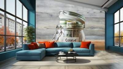 Dollar bills in glass jar isolated on wooden background. Saving money concept for college. Wall mural