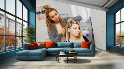 Hairstylist braided afro braids dreadlocks kanekalon pigtails hair of female client in barber salon. Wall mural