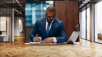 Portrait smiling african american businessman signs contract sit at table for meeting in office with notebook with pen and laptop Wall mural