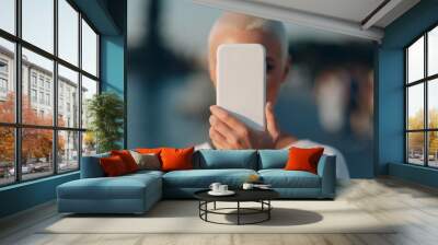 Short haired woman covering close face with smartphone. Mobile phone data security, privacy and confidentiality concept. Wall mural