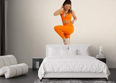 Young positive smiling woman dancing step excercise in orange fitness sport outfit cloth studio isolated shot. Wall mural