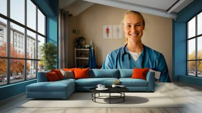 Caucasian nurse standing with cross-arms wearing overalls in neat clinic Wall mural