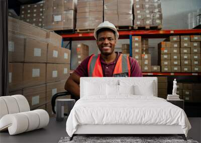 Male factory worker smiling besides packages in warehouse  Wall mural