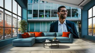 Middle-aged businessman wearing spectacles smiling standing outside banking office building Wall mural