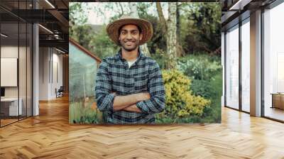 Mixed race male farmer standing next to green house with arms crossed  Wall mural