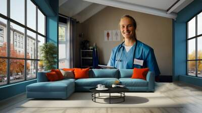 Portrait of young beautiful Caucasian female doctor in scrubs with digital tablet, smiling Wall mural