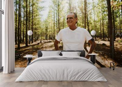 Young caucasian male pensioner exercising and running in the woods, smiling and happy in nature Wall mural