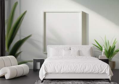 Minimalist wall display featuring a blank frame surrounded by indoor plants in natural light. Wall mural