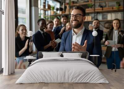 Smiling businessman applauded by colleagues in modern office. Wall mural