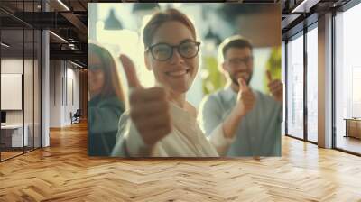 Smiling businesswoman showing thumbs up with colleagues. Wall mural