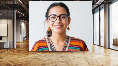 Smiling woman wearing colorful traditional attire and glasses poses against a plain background during daytime. Wall mural