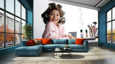 adorable little girl playing with her mother's cosmetic in front of the mirror at home Wall mural