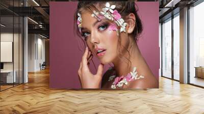 Beautiful caucasian woman with flowers on pink background. Wall mural