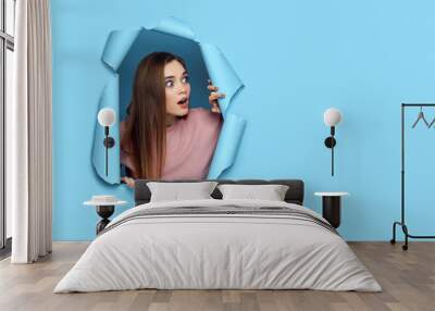 beautiful surprised caucasian woman looking with scared face expression aside in torn paper blue wall. banner for discounts and sales. copy space Wall mural