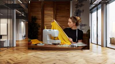 Beautiful young seamstress working on sewing machine Wall mural