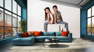 Cute stylish little couple child girl and boy in fashionable clothes sittting together at studio. kids fashion concept. Wall mural