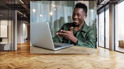 Handsome african american man using computer and smiling. Online video chat with friends Wall mural